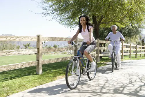 Two women riding hybrid bikes in park