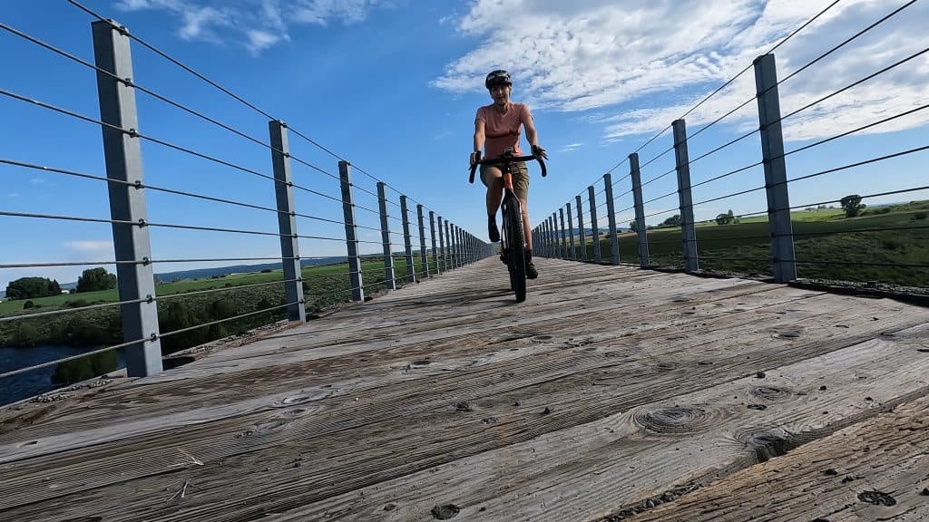 Author, Jennifer, riding gravel bike over trestle bridge